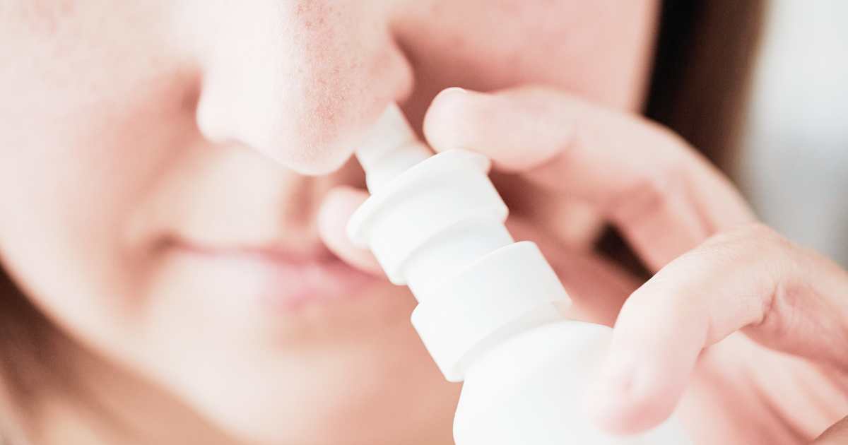 Woman using nasal spray to treat allergies and tinnitus